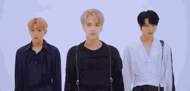 three young men are standing next to each other and one of them is wearing a black sweater with the word calvin klein on it