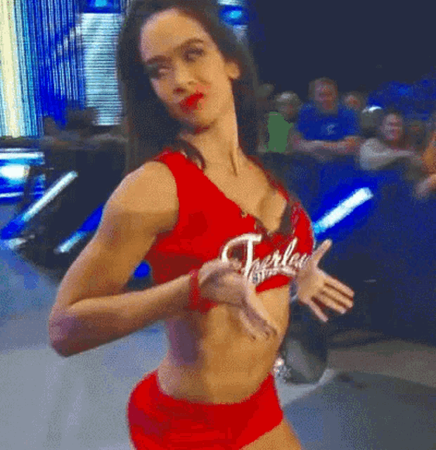 a woman in a red tank top and red shorts is dancing in front of a crowd .