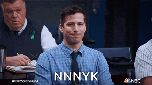 a man in a plaid shirt and tie is sitting at a table and says nnnyk
