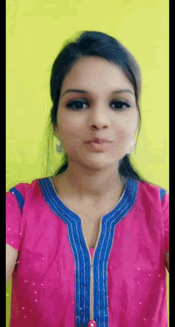 a woman in a pink and blue top is making a face