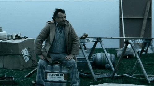 a man sits on a flat pack pub in a field
