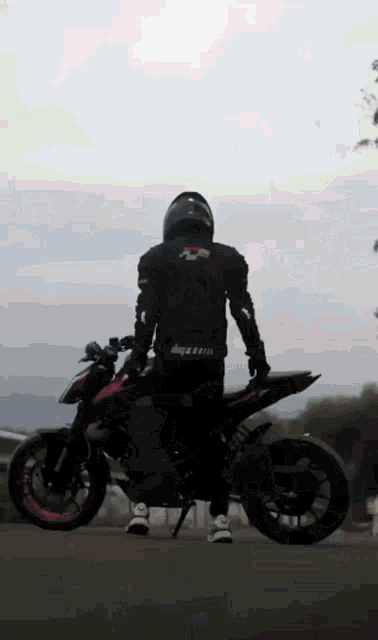 a man is standing on a red motorcycle with a helmet on his head