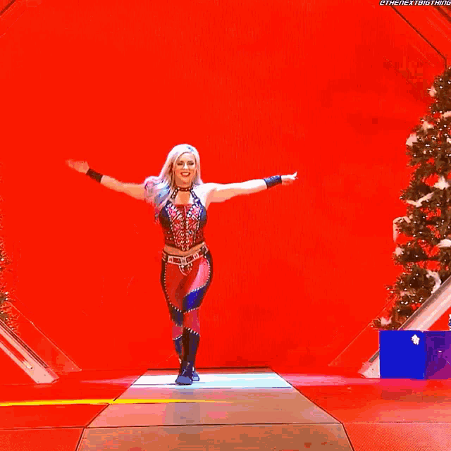 a woman is dancing on a stage with christmas trees behind her
