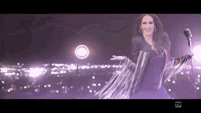 a woman singing into a microphone with tp written on the bottom of the screen