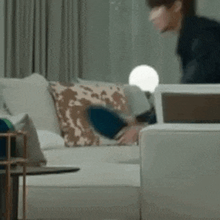 a man is sitting on a couch in a living room with a laptop .
