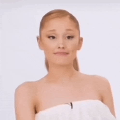 ariana grande is wrapped in a white towel and looking at the camera .