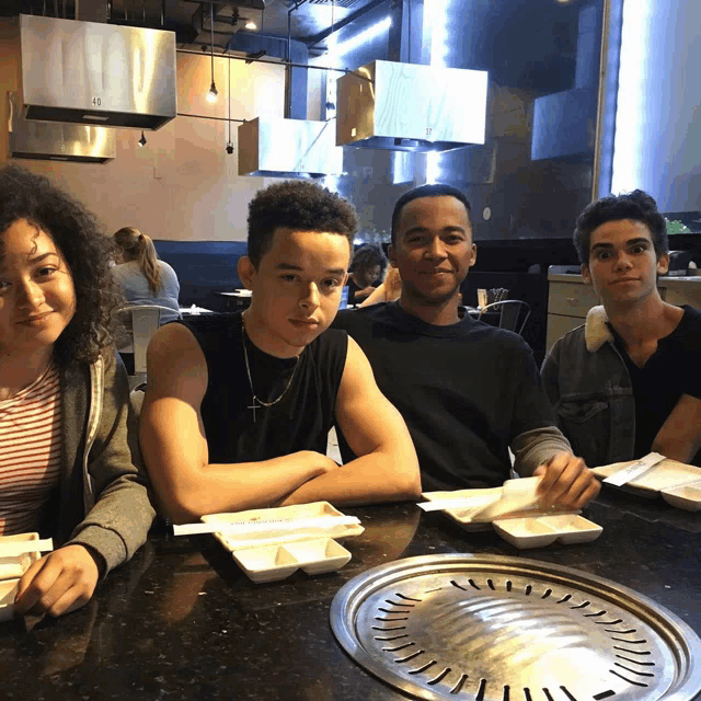 a group of young people are sitting at a table with plates of food and a plate that has the number 49 on it