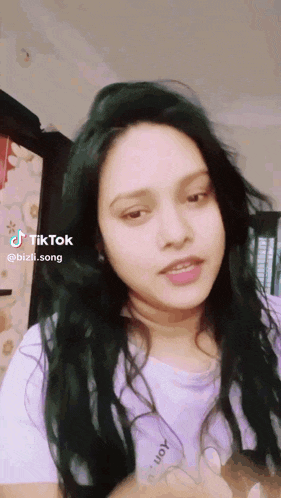 a woman with green hair is wearing a purple shirt that says bizli.song