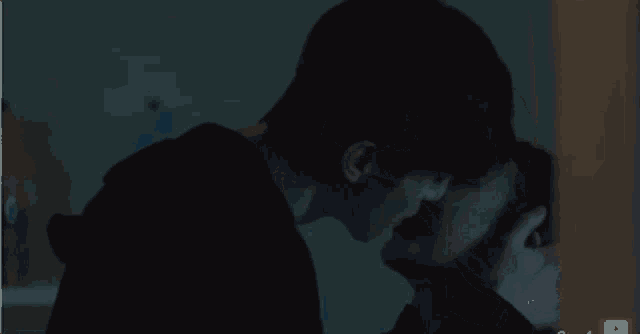 a man and woman are kissing in the dark .