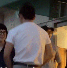 a man in a white shirt is standing next to a woman in glasses