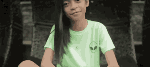 a young girl wearing a green shirt with an alien on the front