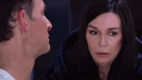 a man and a woman are looking at each other in a dark room