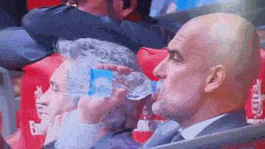 a man in a suit is drinking water from a bottle that says ' aquafina ' on it