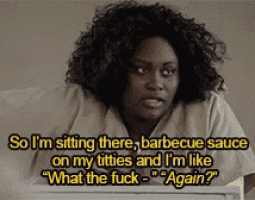 a woman with curly hair is sitting at a table and says so i 'm sitting there barbecue sauce on my titties
