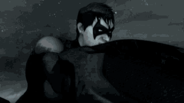 a man in a black and red superhero costume is standing in the dark