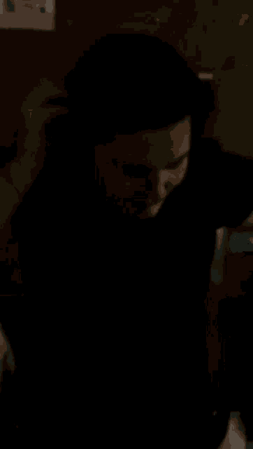 a woman in a black shirt is holding a man 's arm in a dark room .