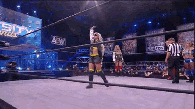 a woman is standing in the middle of a wrestling ring with her hand in the air .