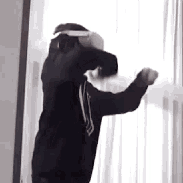 a person wearing a virtual reality headset is standing next to a window .