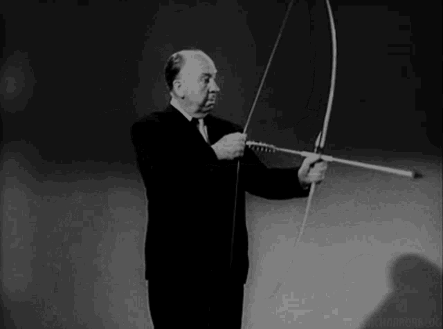 a man in a suit is holding a bow and arrow in his hands .