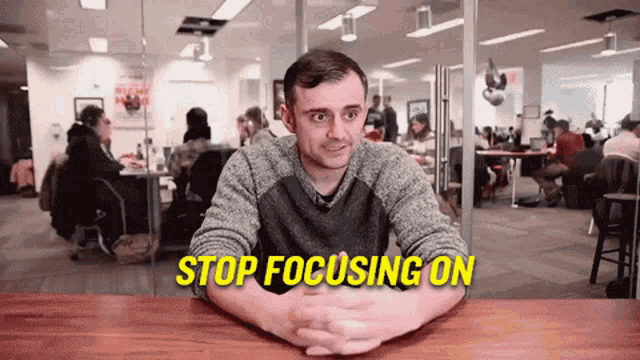 a man sitting at a table with the words stop focusing on written on the screen