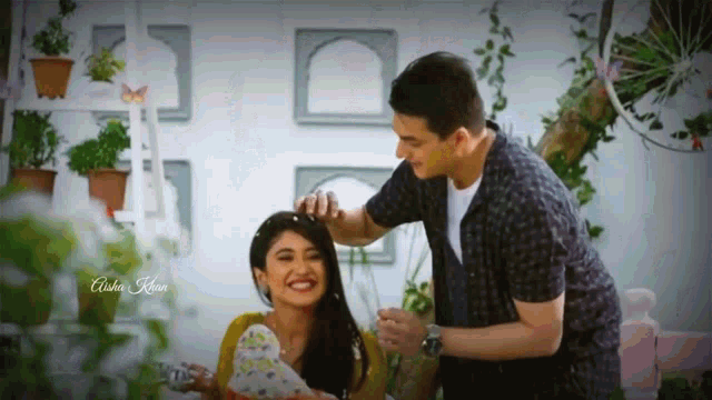 a man putting a flower on a woman 's head with the name aisha khan on the bottom right