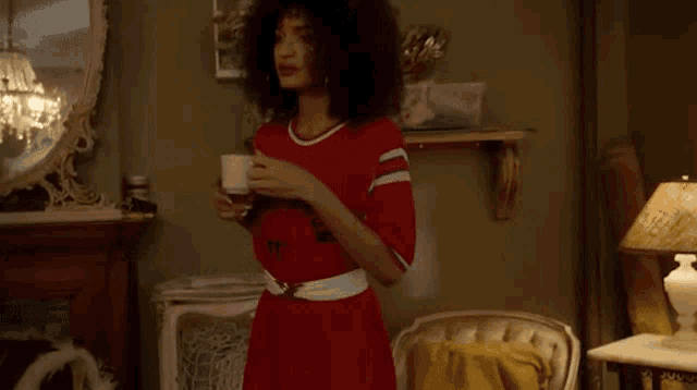 a woman with curly hair is sitting on a couch drinking a cup of coffee .