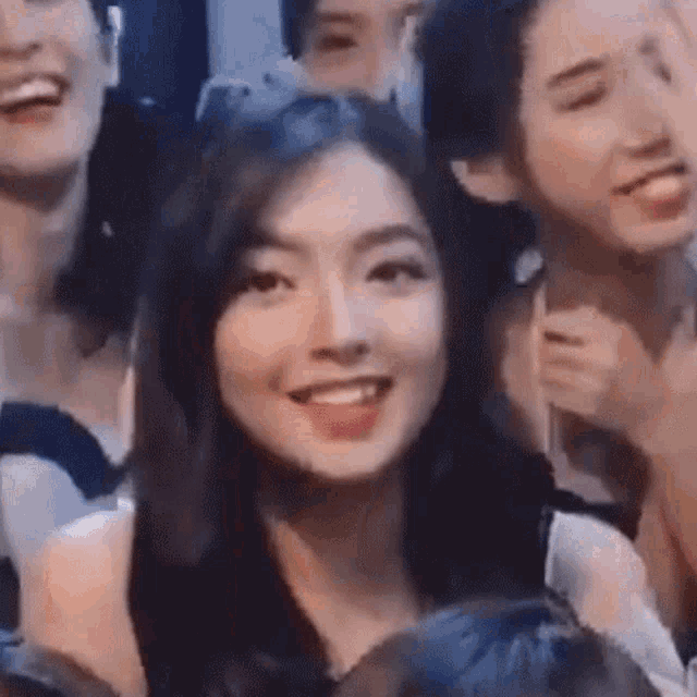 a group of women are sitting in a row and smiling at the camera .