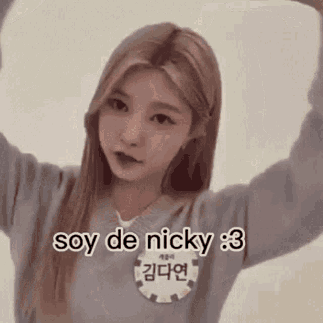 a girl with blonde hair is wearing a grey sweater and a name tag that says soy de nicky 3 .