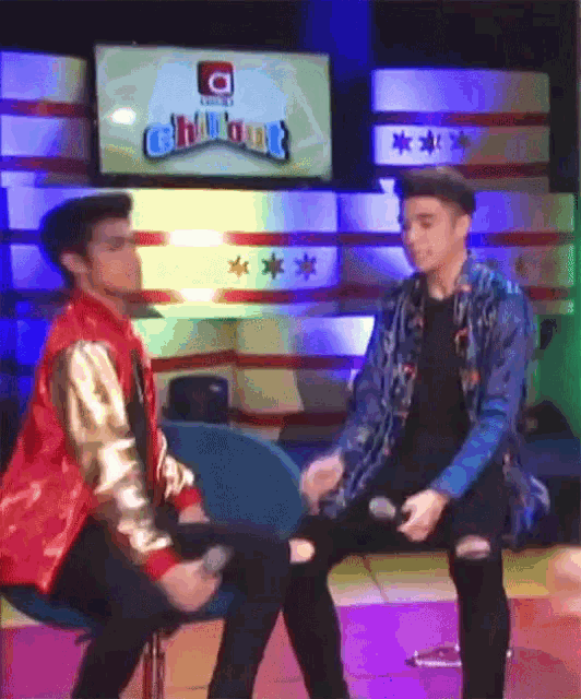 two young men are sitting next to each other in front of a tv screen that says chill out