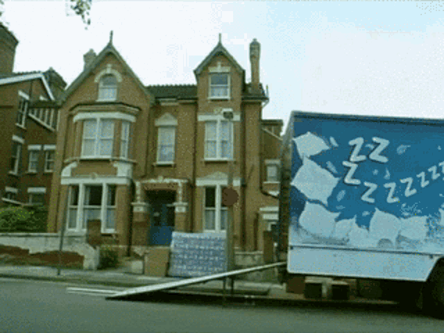 a blue and white truck with zzz written on it is parked in front of a brick building