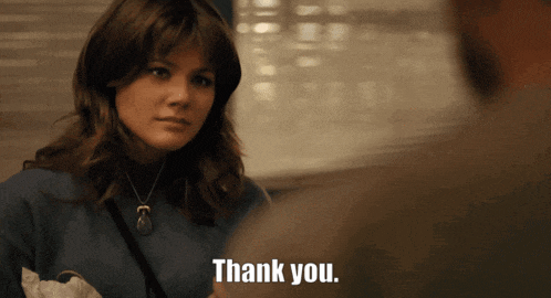 a woman wearing a blue sweater says thank you