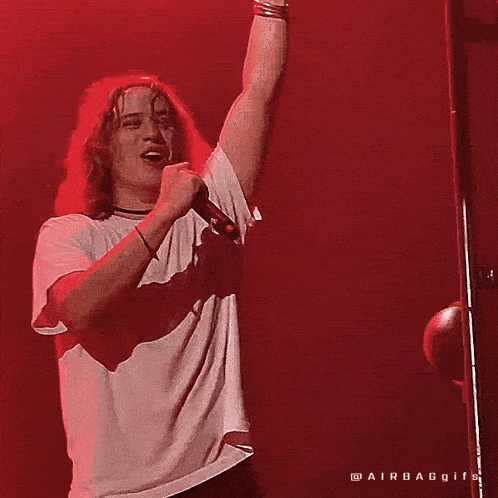 a man singing into a microphone with a red background
