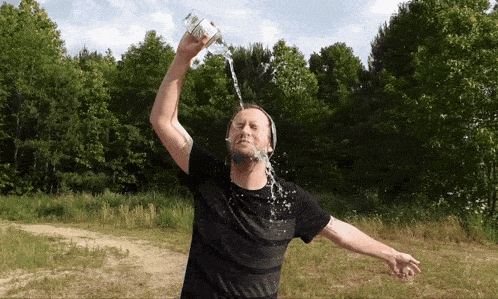 a man in a black shirt is pouring water from a bottle on his head