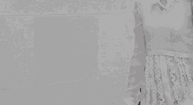 a woman in a white dress is standing in front of a white wall .