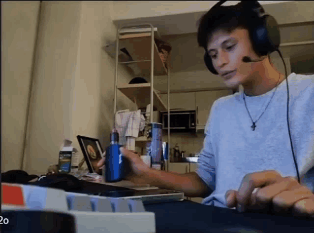 a man wearing headphones and a cross necklace is holding a device