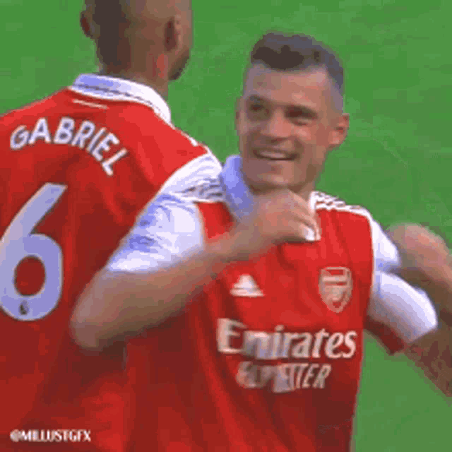 two soccer players in red jerseys are hugging each other on the field .