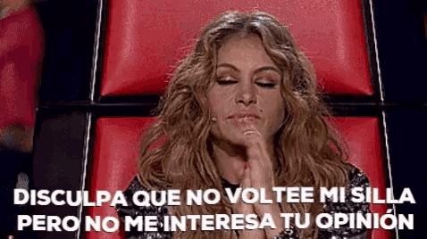 a woman is sitting in a red chair with her eyes closed and a caption in spanish