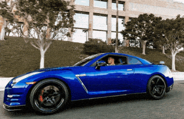 a blue sports car is driving down a street