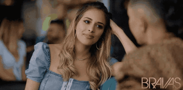 a woman in a blue dress looks at a man in a bravas ad