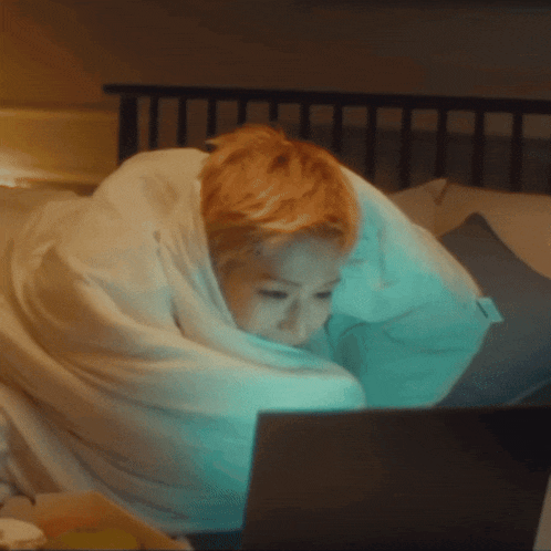 a person wrapped in a blanket is using a laptop computer