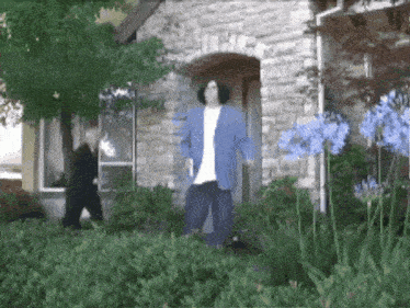 a man in a blue jacket stands in front of a brick house