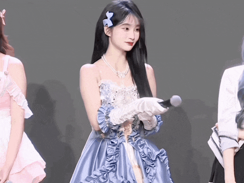 a woman in a blue dress holds a microphone
