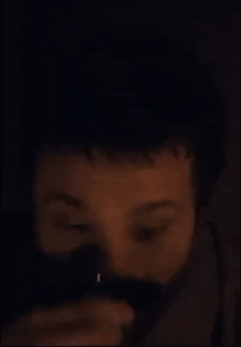 a close up of a man 's face with a beard in the dark