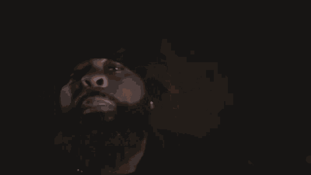 a man with a beard is giving the middle finger to the camera in a dark room .