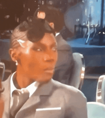 a woman wearing a suit and tie is sitting in a chair
