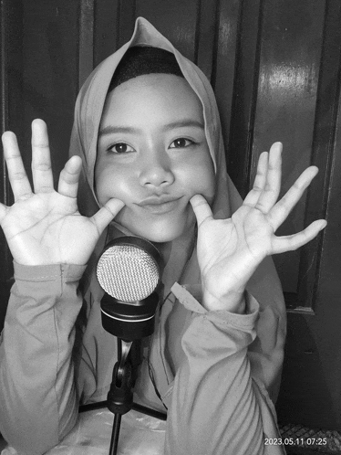 a black and white photo of a girl making a face with her hands