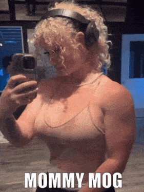 a woman wearing headphones takes a selfie in front of a mirror with the caption mommy mog