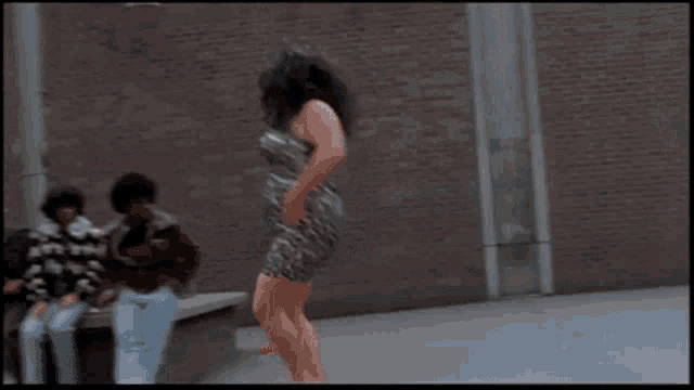 a woman in a leopard print dress is dancing in front of people sitting on a bench .