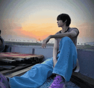 a person wearing purple shoes sits on a railroad track