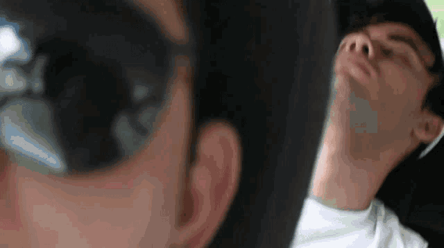 a man wearing sunglasses and a white shirt is sleeping in a car seat